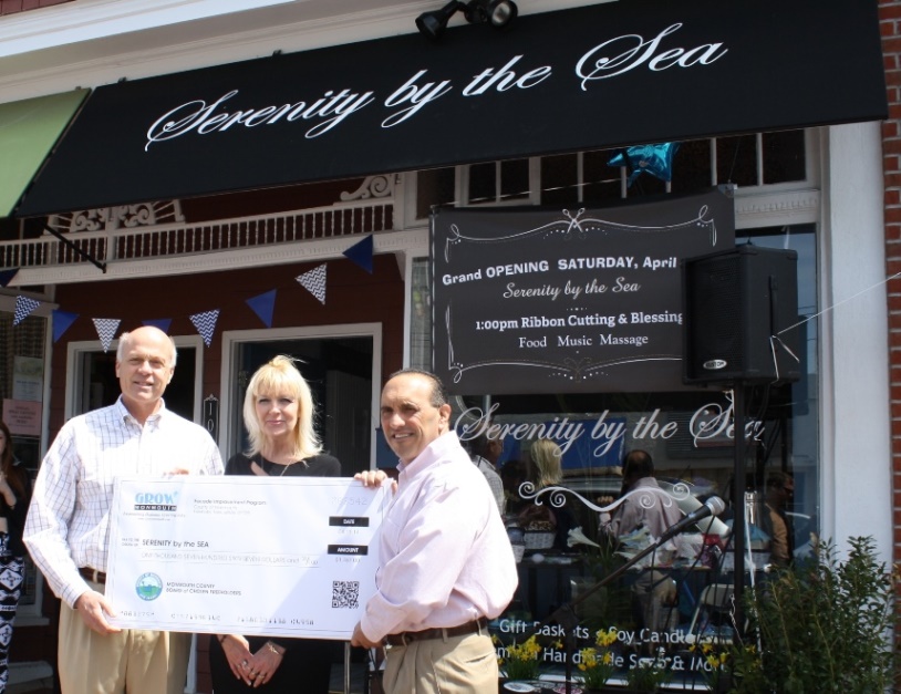 Serenity by the Sea owner Jill Naughton-Capone accepts a Façade Improvement Program reimbursement check for $1,767 from Freeholder Deputy Director Gary J. Rich, Sr. and Freeholder Thomas A. Arnone on April 19, 2014 in Belmar, NJ.